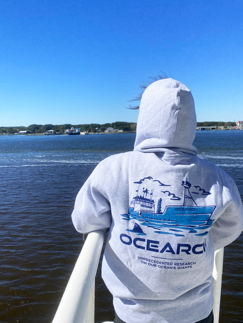 Person wearing mothership hoodie overlooking water
