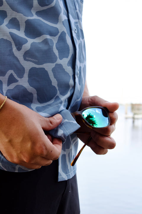 man wiping glasses on light blue Ocearch camo shirt