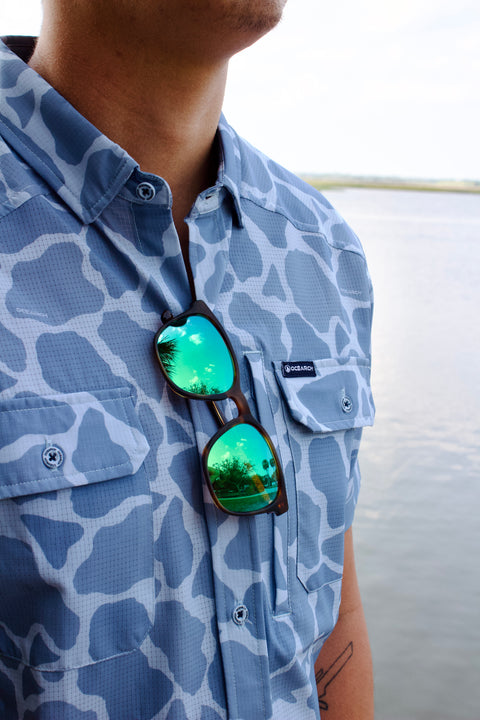 closeup of sunglassing hanging from light blue Ocearch camo shirt